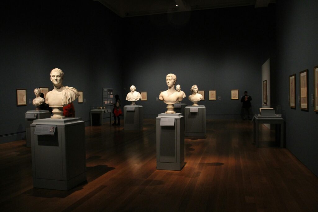 An art gallery with classical sculptures and framed art, showcasing elegant indoor lighting and design.