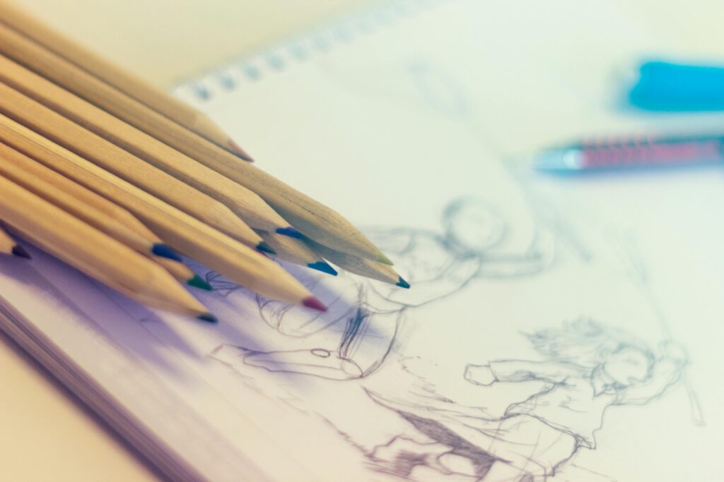 Close-up of colored pencils on sketch-filled notepad, perfect for creativity concepts.